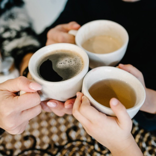 Manos de personas con tazas de té y café. SERHII SOBOLEVSKYI