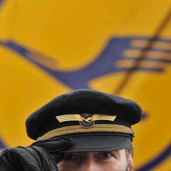 FILED - 22 February 2010, Frankfurt/Main: A Lufthansa pilot stands in front of the Lufthansa logo at Frankfurt Airport. Photo: picture alliance / Boris Roessler/dpa Picture Alliance / Boris Roessle / Dpa