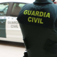 Un agente de la Guardia Civil, de espaldas, junto a un vehículo oficial. GUARDIA CIVIL