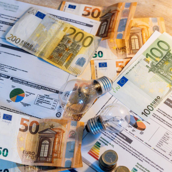 Dos bombillas sobre billetes, monedas y facturas Ricardo Rubio - Europa Press