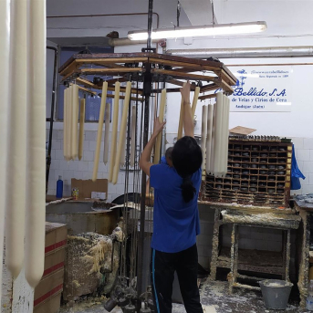 Una trabajadora de Cera Bellido cuelga cirios. CERA BELLIDO