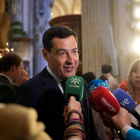 El presidente de la Junta de Andalucía, Juanma Moreno, atiende a los medios antes de la salida de La Borriquita en la iglesia de El Salvador de Sevilla. JOAQUÍN CORCHERO/EUROPA PRESS