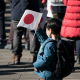02 January 2023, Japan, Tokyo: A boy holds a Japanese national flag during the New Year's appearance by the Japanese royal family at the Imperial Palace. Photo: -/ZUMA Press Wire/POOL/dpa -/ZUMA Press Wire/POOL/dpa