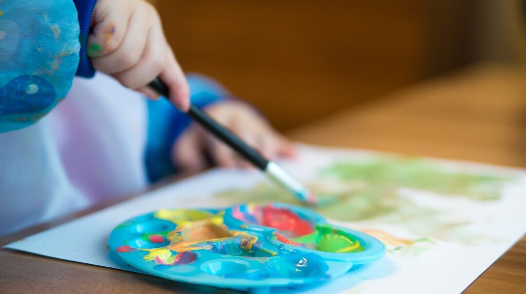 Imagen de un niño pintando con un pincel y témperas. Fuente Pixabay