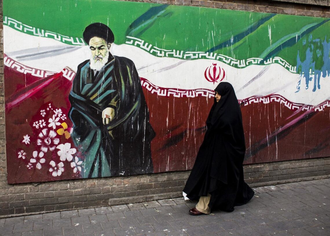 Archivo - Una mujer junto a un mural con la bandera iraní y el ayatolá Ruholá Jomeini en Teherán (archivo)DANI SALVÀ / VWPICS / ZUMA PRESS / CONTACTOPHOTO