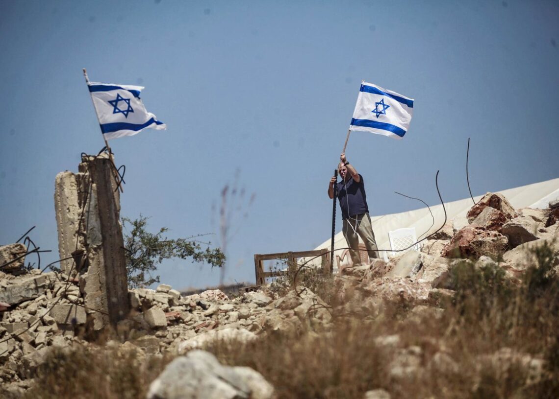 Archivo - Un colono israelí iza una bandera de Israel en tierras palestinas durante un ataque a la ciudad de Bruqin, cerca de la ciudad de Salfit, en el norte de CisjordaniaEuropa Press/Contacto/Nasser Ishtayeh - Archivo