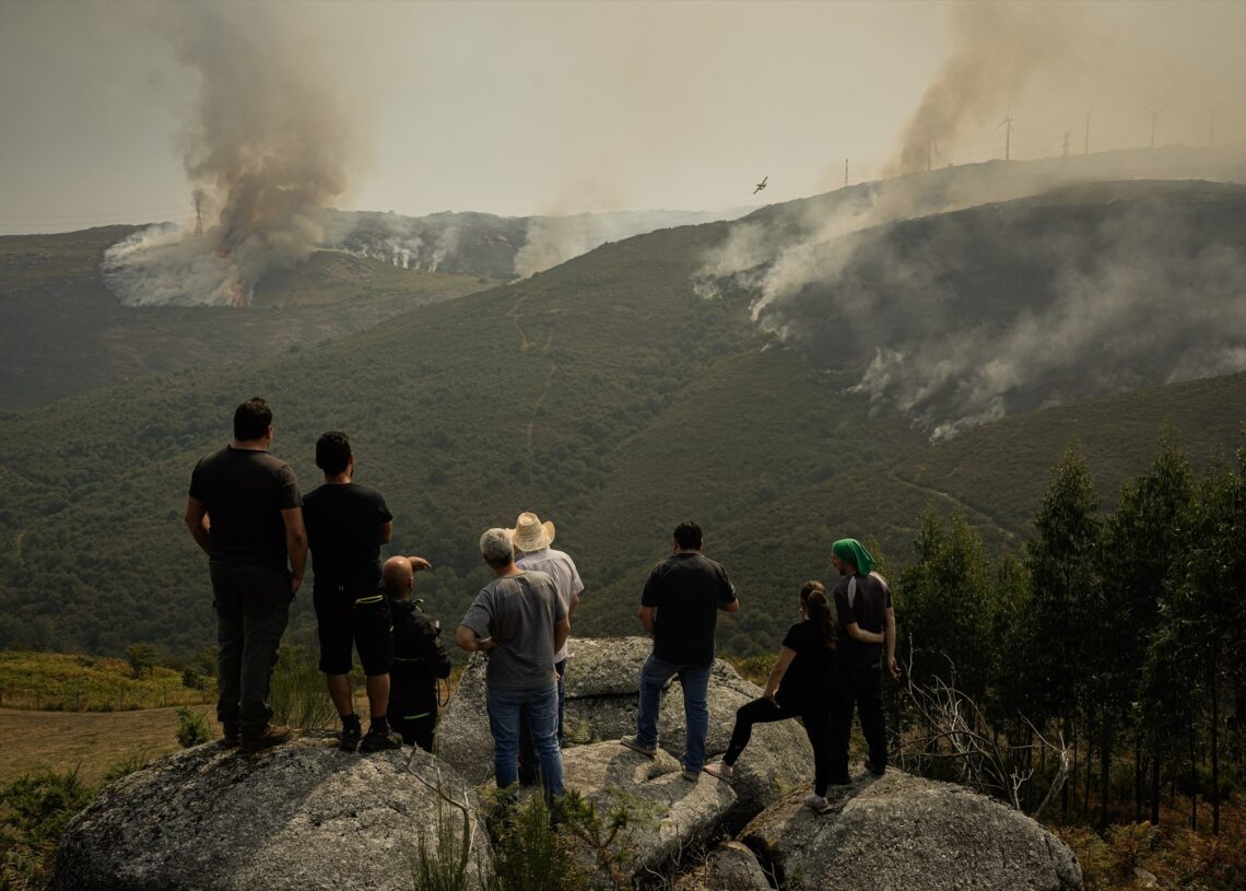 Varias personas ven cómo los efectivos aéreos trabajan en la extinción del incendio de Avión (Ourense). Adrián Irago/Europa Press.