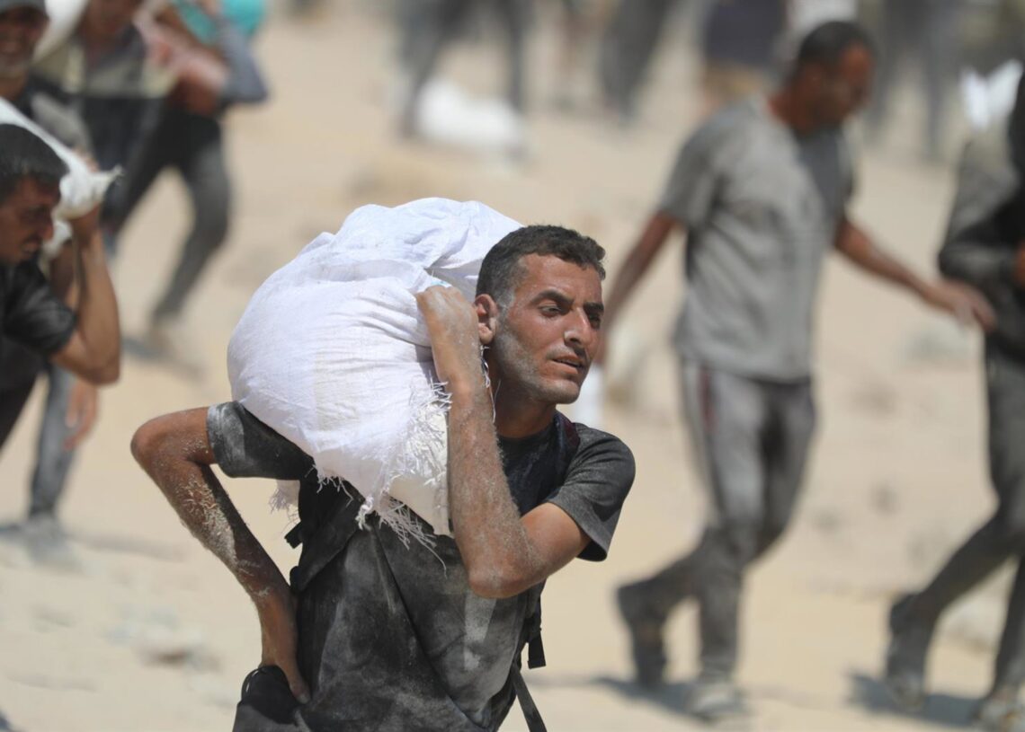 Imagen de archivo de palestinos cargando con sacos en Gaza.Omar Ashtawy/APA Images via ZUMA / DPA
