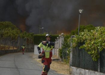 Dos bomberos colaboran en la extinción del incendio, a 12 de agosto de 2025, en Seixalbo, Ourense, Galicia (España).Rosa Veiga - Europa Press