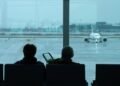 Archivo - Dos personas esperan sentadas frente a un avión aparcado en la pista del aeropuerto de El PratDavid Zorrakino - Europa Press - Archivo