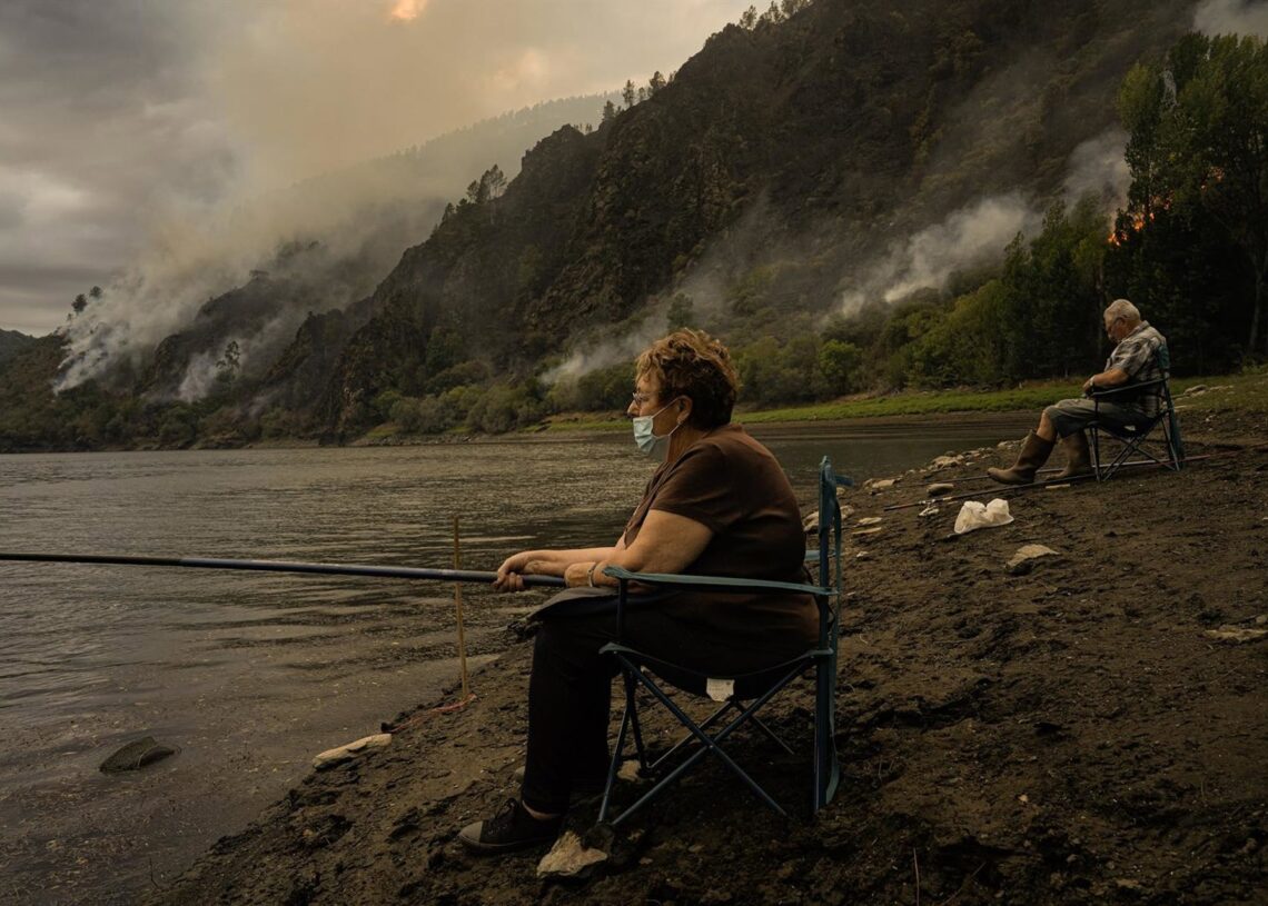 Una pareja pesca cerca el fuego. Adrián Irago - Europa Press