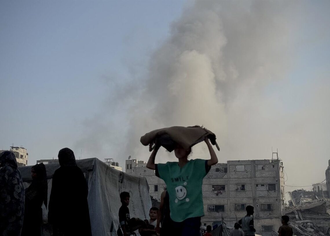 En el centro, un niño transporta un saco de comida. Al fondo, columna de humo por ataques de Israel sobre Jan Yunis, en el sur de la Franja de Gaza Europa Press/Contacto/Abdallah Alattar