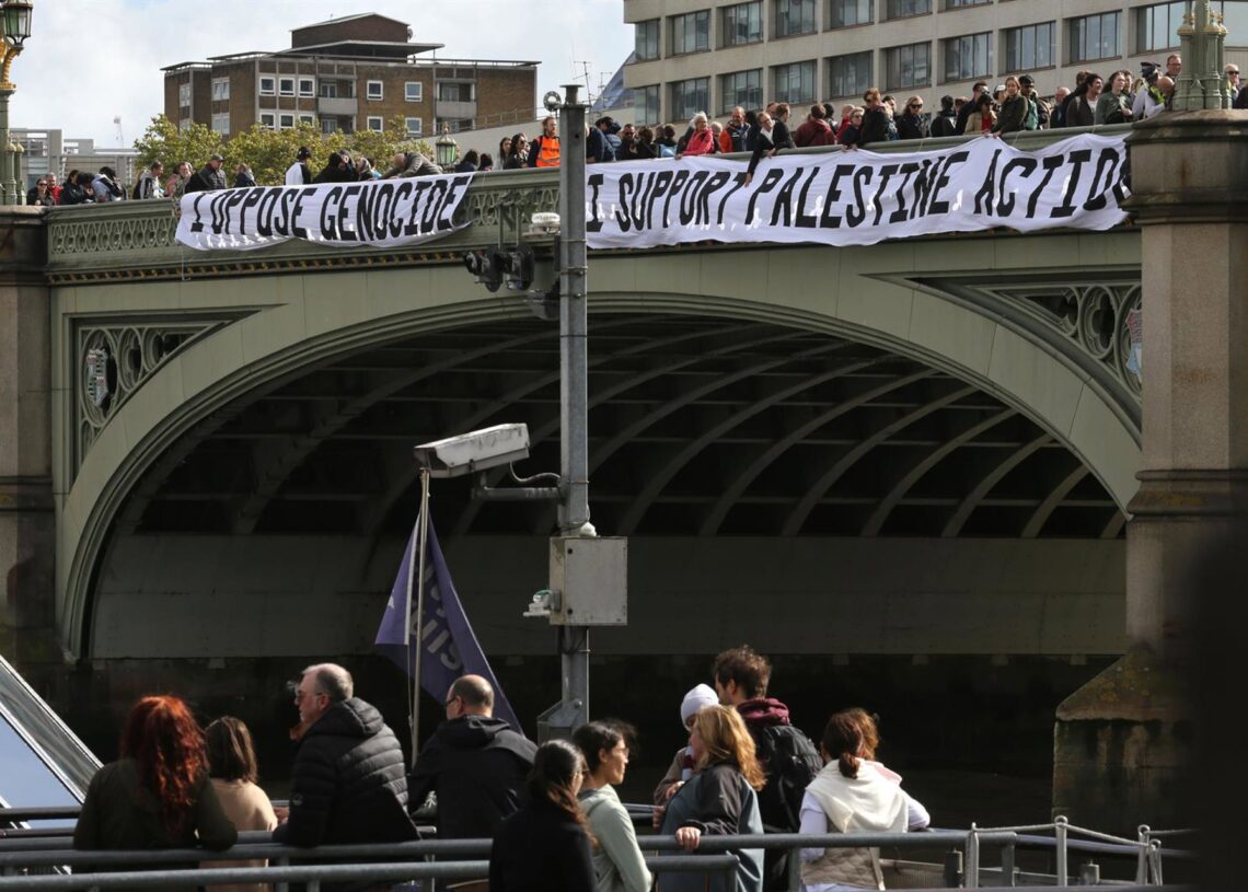 Un grupo de activistas sostiene dos pancartas en el lateral del puente de Westminster con el lema "Me opongo al Genocidio y Apoyo la Acción Palestina" durante un acto de protesta, rodeados de policías, en Londres, Reino UnidoEuropa Press/Contacto/Martin Pope