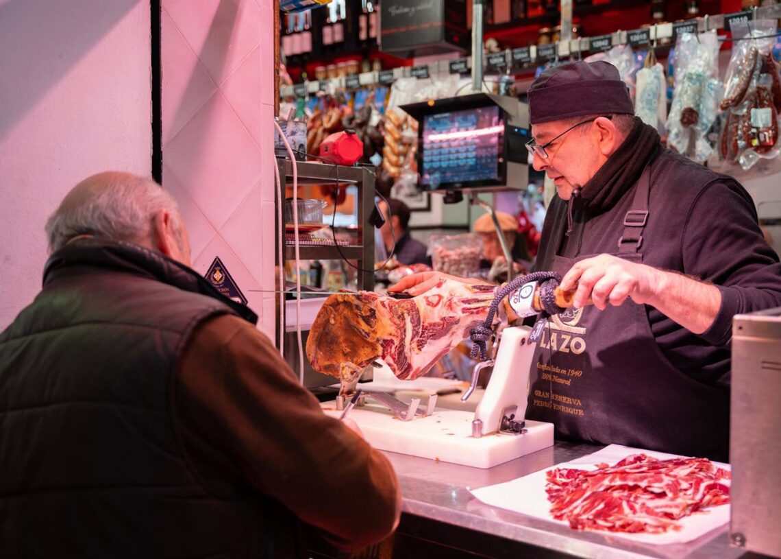 Archivo - Un autónomo atendiendo a un cliente en su puesto de un mercado de abastos de SevillaMaría José López - Europa Press - Archivo