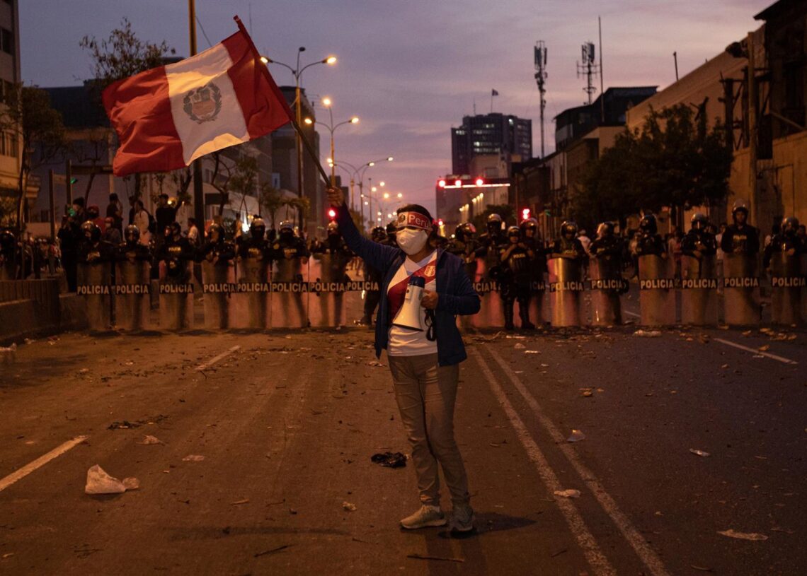 Archivo - Una manifestante porta un bandera en las calles de Lima ante un pelotón de la PolicíaLucas Aguayo Araos/dpa - Archivo