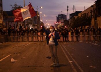 Archivo - Una manifestante porta un bandera en las calles de Lima ante un pelotón de la PolicíaLucas Aguayo Araos/dpa - Archivo