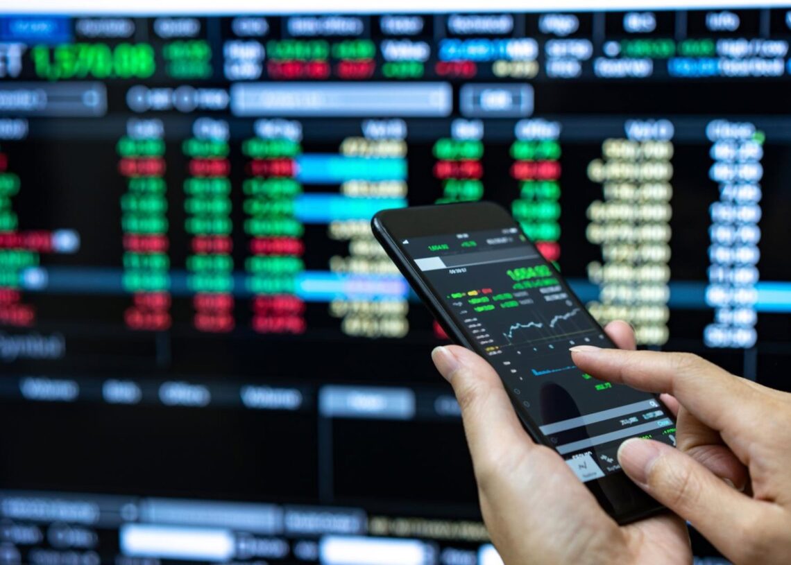 Archivo - Businessman checking stock market data. He using a mobile phone. Analysis economy data on forex earn graph.WITTHAYA PRASONGSIN - Archivo