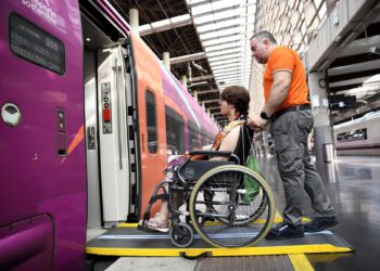 Archivo - Un asistente de Adif Acerca ayuda al embarque de una persona en un trenADIF - Archivo