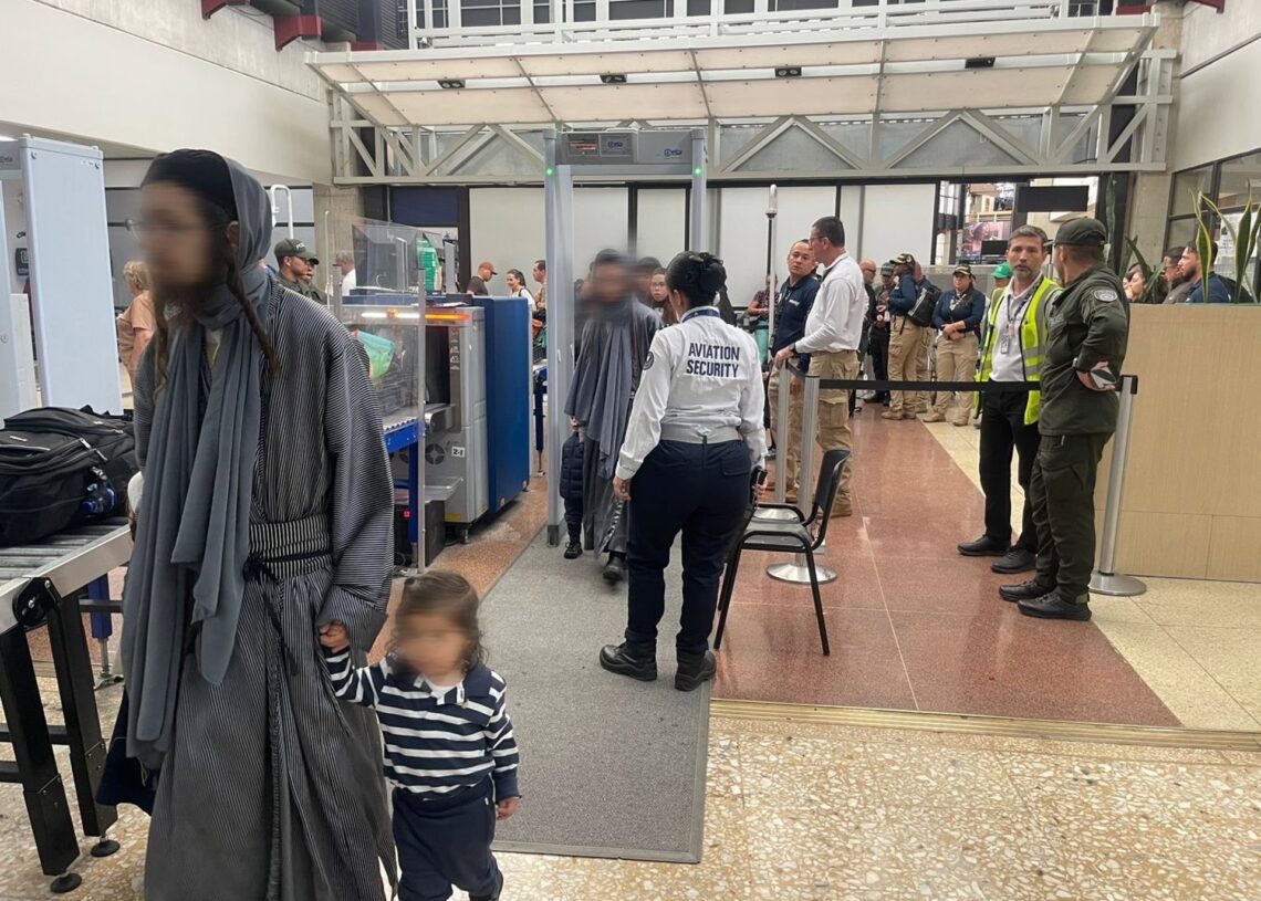 Un hombre de la secta judía Lev Tahor camina junto a una niña en un control de seguridad durante su traslado a Estados Unidos, tras la expulsión de Colombia de nueve adultos de la secta junto a 17 menores que serán entregados a los servicios socialesMIGRACIÓN COLOMBIA EN X